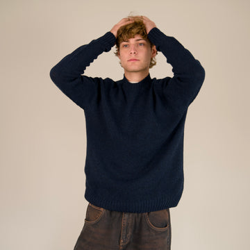 Man wearing a navy sweater against a beige background