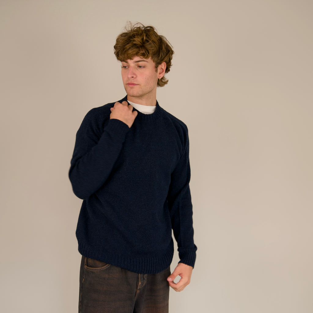 Person wearing a navy sweater against a beige background